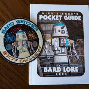 Könnte beinhalten: Ein weißer und blauer Taschenführer mit dem Titel "Nick Tierce's Pocket Guide to Bard Lore 2025". Das Cover zeigt einen Roboter mit einem blauen Kopf und einem weißen Körper.