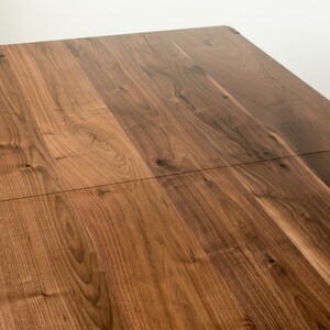 K&ouml;nnte beinhalten: Nahaufnahme einer Tischplatte aus Holz mit nat&uuml;rlicher Holzmaserung. Die Tischplatte besteht aus zwei zusammengef&uuml;gten Holzst&uuml;cken.