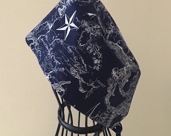 May include: A navy blue surgical cap with a white nautical map print and a white compass star design.