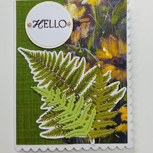 Op de afbeelding: Een groene kaart met een witte cirkel waarop "HELLO" staat en een groen varenbladontwerp.
