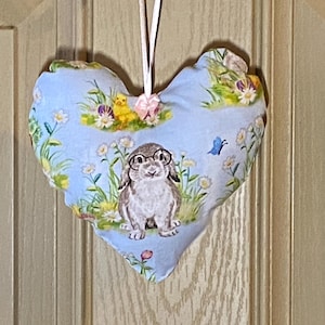 May include: A blue heart-shaped fabric ornament with a bunny wearing glasses, chicks, and flowers.