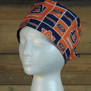 May include: A blue and orange scrub hat with the Auburn University logo and the words "Tigers" repeated throughout the design.