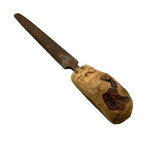 May include: A vintage metal file with a wooden handle. The file has a long, tapered, and textured metal blade. The handle is made of light-colored wood with a natural grain and a dark knot. The tool is designed for shaping or smoothing materials.