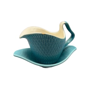 May include: A vintage turquoise ceramic gravy boat and saucer set. The gravy boat has a textured basketweave pattern and a curved handle. The interior is cream-colored. The saucer has a matching wavy design.