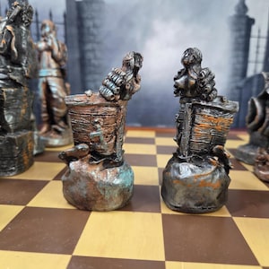 May include: Chess set with detailed, weathered-look pieces. The pieces are in shades of brown, gray, and teal, with a rustic, aged appearance. The chess board has a classic brown and tan checkered pattern.