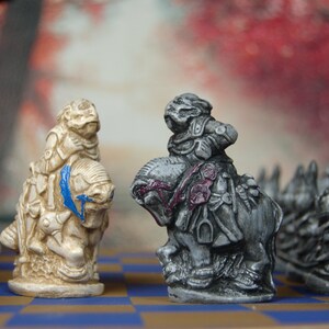 May include: A chessboard with two chess pieces, a white knight and a black knight, facing each other. The white knight is on the left side of the board and the black knight is on the right side of the board. There are other chess pieces in the background.