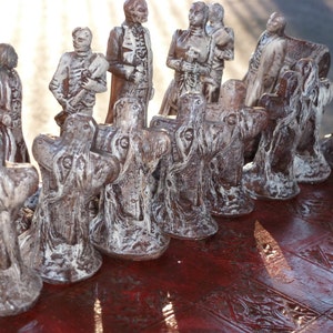 May include: A detailed chess set with brown and white figures. The chess pieces are sculpted in a unique style, with a dark brown finish and white highlights. The chessboard has a dark red, patterned surface.