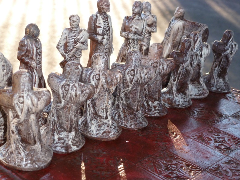 May include: A detailed chess set with brown and white figures. The chess pieces are sculpted in a unique style, with a dark brown finish and white highlights. The chessboard has a dark red, patterned surface.