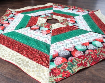 May include: A green, red, and white patchwork Christmas tree skirt with a variety of holiday patterns, including ornaments, snowflakes, and poinsettias.