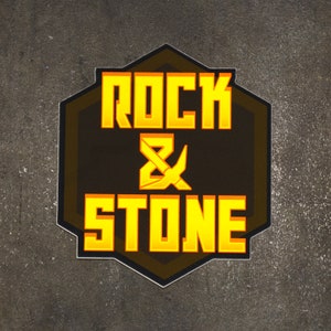 May include: A black and yellow hexagonal sticker with the text "Rock & Stone" in a bold, yellow font.