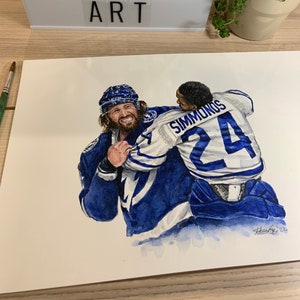 May include: Watercolor painting of two hockey players in blue jerseys, one with the name "Simmonds" and the number "24" on the back. The player in the front is holding the player in the back, both smiling. The painting is signed "Mike Nguyen 22".