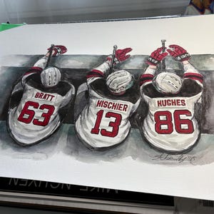 May include: Watercolour painting depicting three hockey players in white and black jerseys with red detailing. Each jersey features a different number: 63, 13, and 86, and the players' names. The players are raising their hockey sticks.