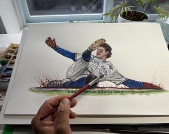 以下が含まれることがあります： 野球選手がホームベースにスライディングする水彩画。選手は前面に「JAYS」と書かれた白と青のユニフォームを着ています。アートワークは署名入りで、「2023 World Series GM7」と日付が記されています。
