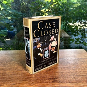 May include: A gold hardcover book titled "Case Closed" with a black and white photo of Lee Harvey Oswald on the cover. The book is about the assassination of JFK and is written by Gerald Posner.