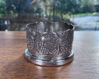 May include: Silver-toned metal wine glass holder with an embossed grapevine design.