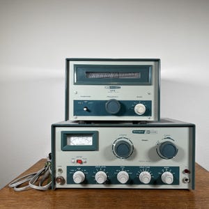 May include: Vintage Heathkit VFO and Model 3040 radio equipment. The devices are gray with teal accents and feature dials, meters, and switches. The VFO is stacked on top of the Model 3040, with a series of knobs and dials.