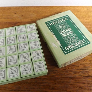 May include: A box of 1/2 inch square micro cover glasses, labeled "Hellige Checker Brand Non Corrosive Cover Glasses". The box contains 36 individual squares.