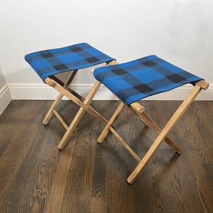 May include: Two wooden folding chairs with blue and black plaid fabric seats.