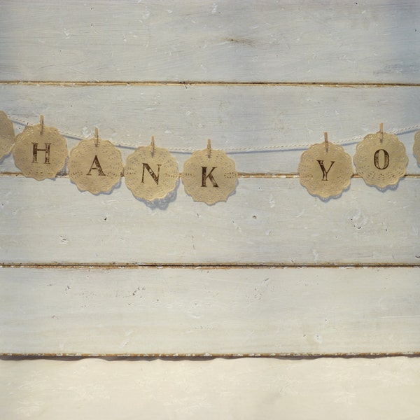 Hand-dyed paper doily garland with 'thank you' message for wedding guests.