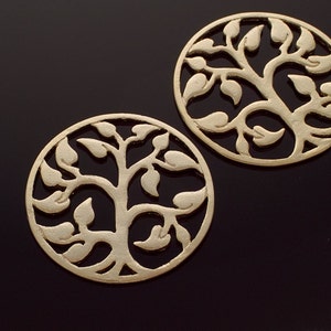 May include: Two gold-colored metal charms in the shape of a tree of life. The charms are circular and have a delicate, intricate design.