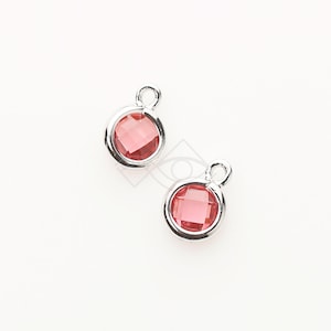 May include: Two silver charms with a red crystal in the center. The charms have a loop at the top for attaching to a necklace or bracelet.