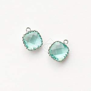 Può includere: Due ciondoli quadrati in vetro blu chiaro con cornici in metallo argentato. I ciondoli hanno un design sfaccettato e un anello nella parte superiore per attaccarli ai gioielli.