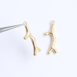 May include: Two gold-coloured metal coral branch charms with a loop at the top for attaching to jewellery or other crafts.