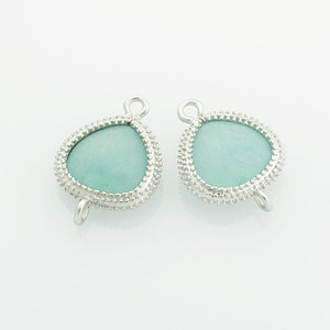 May include: Two silver-toned metal clasps with a light blue gemstone in the center. The clasps have a loop on each side for attaching to a necklace or bracelet.