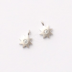 May include: Two silver star-shaped charms with a clear rhinestone in the center. Each charm has a loop at the top for attaching to jewelry.