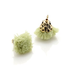 May include: Two green fluffy pom-poms with gold metal caps. The pom-poms are soft and have a fuzzy texture.