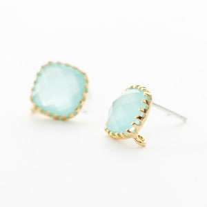 May include: A pair of gold earrings with light blue square-shaped gemstones. The gemstones have a faceted design and are surrounded by a gold border.