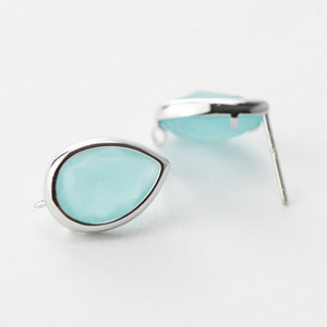 Puede incluir: Un par de pendientes de plata en forma de lágrima con acentos de piedras preciosas azul claro.