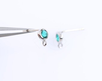 May include: A pair of silver earring findings with a small, round, teal-colored gemstone attached to each.