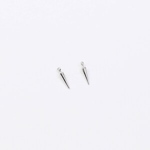 May include: A pair of silver spike earrings with a pointed design.