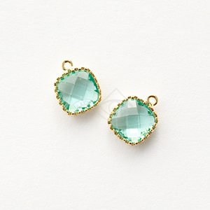 Può includere: Due ciondoli quadrati in vetro verde chiaro con cornici in metallo dorato. I ciondoli hanno un design sfaccettato e un anello in cima per attaccarli a gioielli.