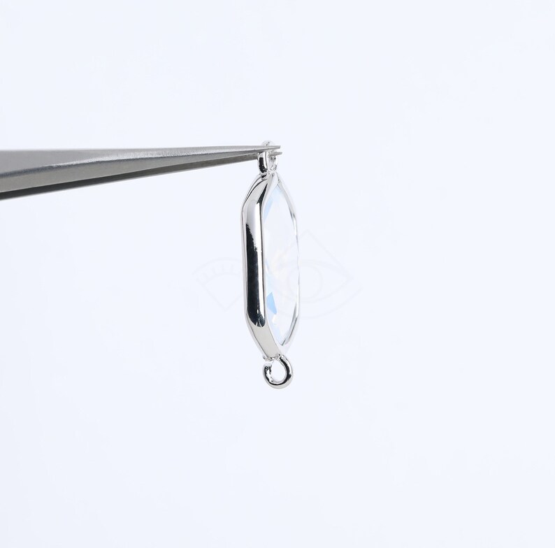 May include: A silver-toned pendant with a clear, faceted, hexagonal charm and a silver loop for attaching to a chain or cord.