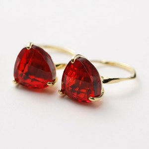 May include: A gold ring with two large, red, triangular gemstones. The ring is made of a thin, twisted band.