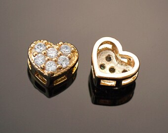 May include: Two gold heart-shaped charms, one with clear cubic zirconia stones and the other with an open back.