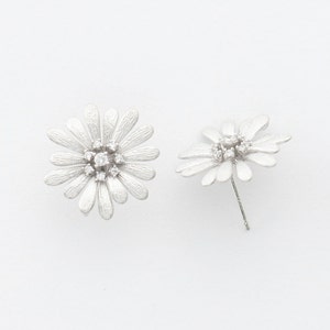 May include: A pair of silver daisy earrings with small clear stones in the center of each flower.