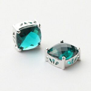 May include: A pair of silver earrings with square-shaped teal gemstones.