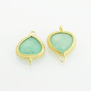 May include: Two gold-tone pendant connectors with a green gemstone in the center. The connectors have a textured edge and a loop on the top and bottom.