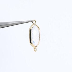 May include: Gold-toned pendant with a clear faceted gemstone. The pendant has two loops for attaching a chain or cord.