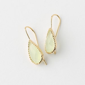 May include: A pair of gold teardrop earrings with a light green gemstone in each. The earrings have a delicate, beaded edge.