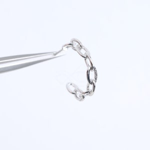 Puede incluir: Un anillo de cadena plateado con un acabado texturizado. El anillo está hecho de múltiples eslabones ovalados conectados.