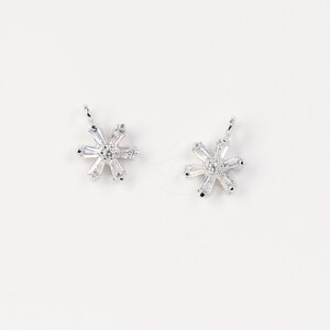 May include: Two silver snowflake charms with clear crystal accents.