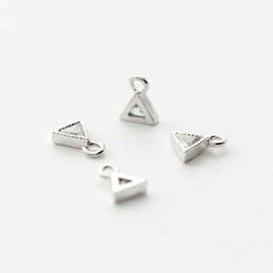 May include: Four silver triangle charms with clear crystal accents. Each charm has a small loop for attaching to jewelry.