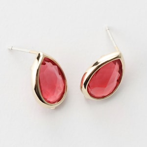 May include: A pair of gold teardrop earrings with red crystal stones.