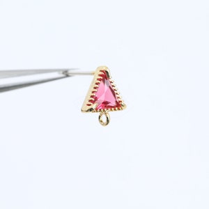 May include: Gold triangle pendant with a red gemstone and a loop for attaching a chain.