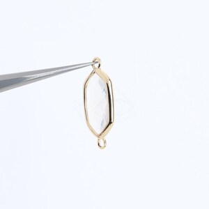 May include: Gold-toned metal pendant with a clear hexagonal glass insert. The pendant has a loop at the top and a smaller loop at the bottom.