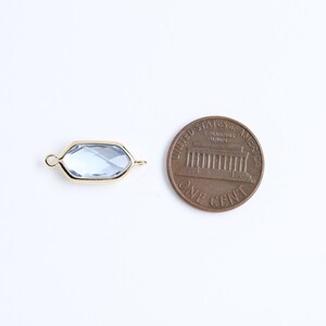 May include: A gold-toned connector with a light blue faceted glass insert. The connector is about the size of a US penny.